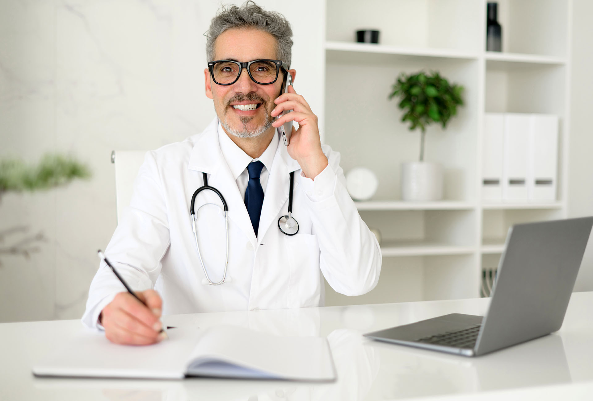 Erfahrener, selbstbewusster Oberarzt mit grauen Haaren beim Telefonat