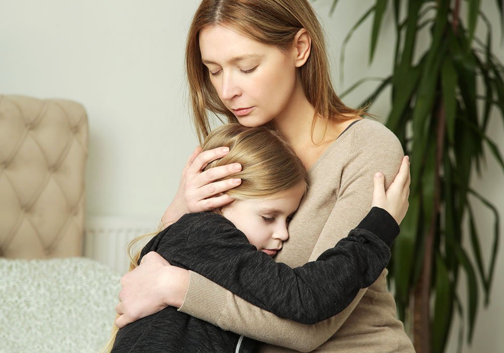 Liebevolle, besorgte Mutter, die ihr trauriges kleines Mädchen tröstet 